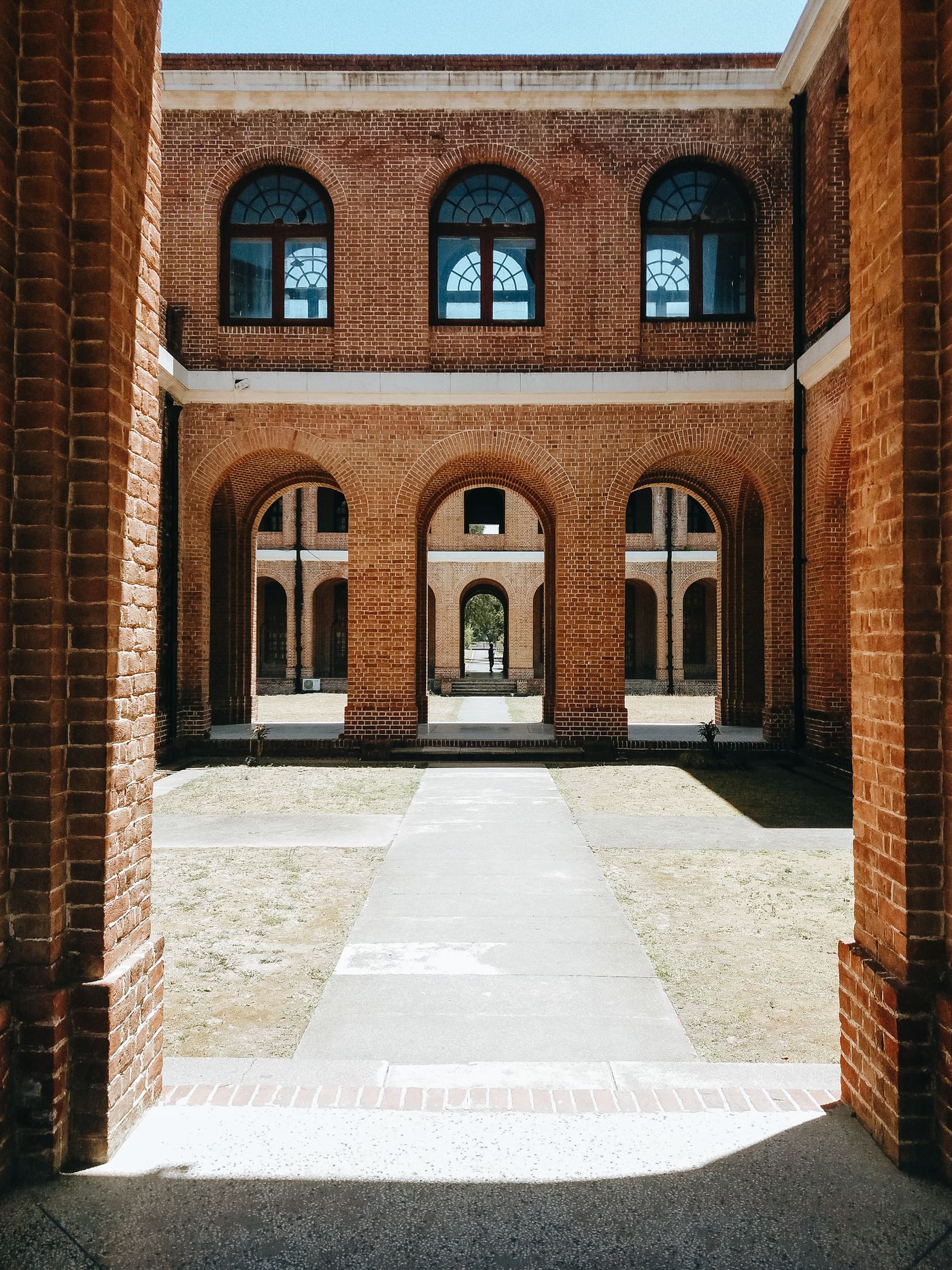Sunlit brick courtyard with repeated arches